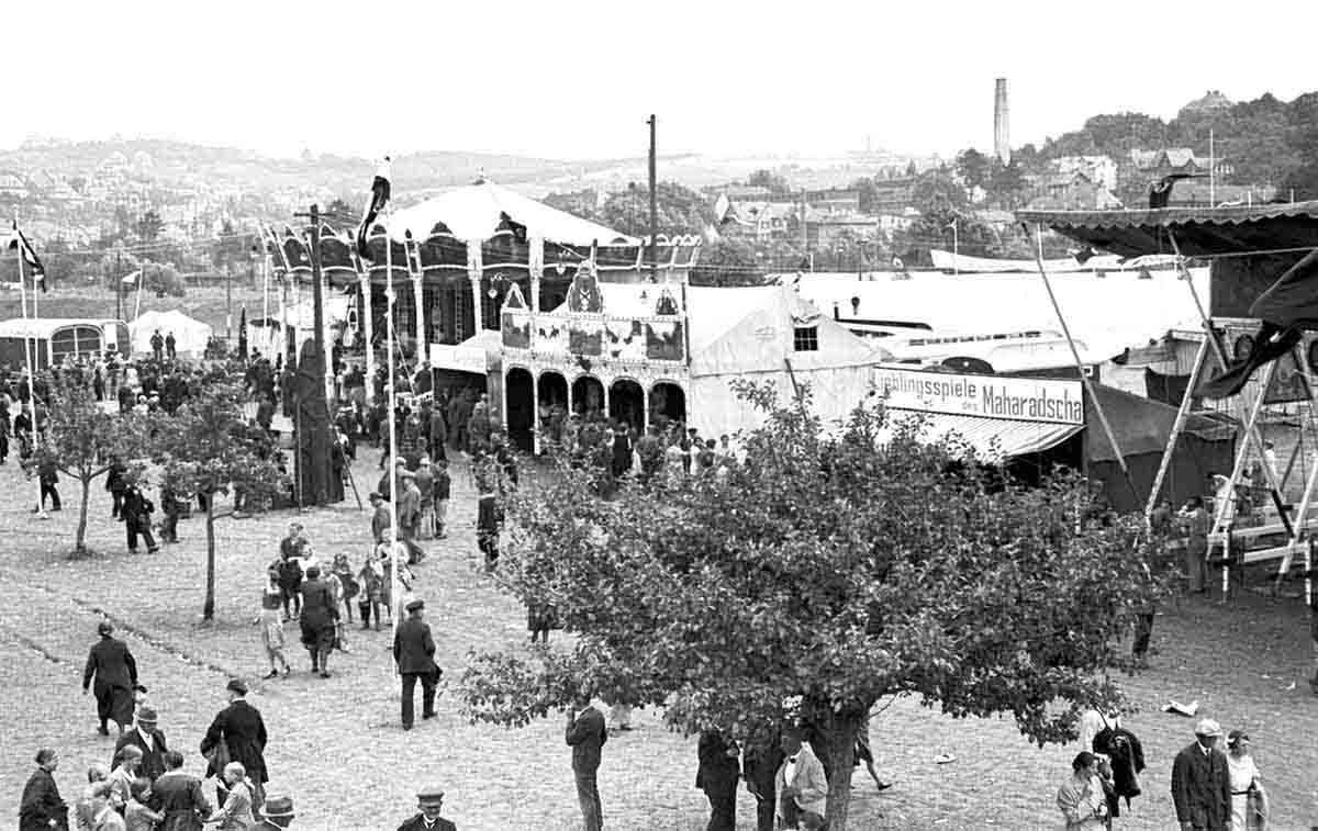 Kirmes auf dem Ochsenfest 1933 V.r.n.l.: Schiffsschaukel, Magier, Schießbude, Kettenkarussell unter Hakenkreuzfahnen